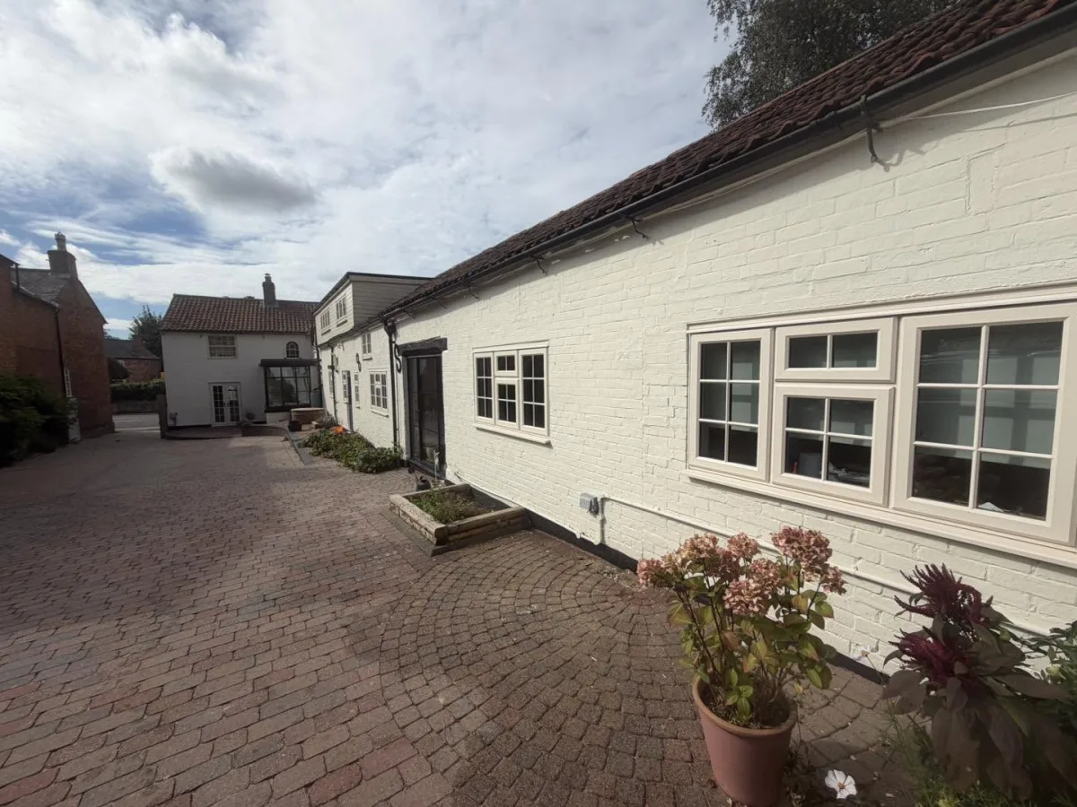 Long white painted brick cottage range with a block paved courtyard, repointed and repainted