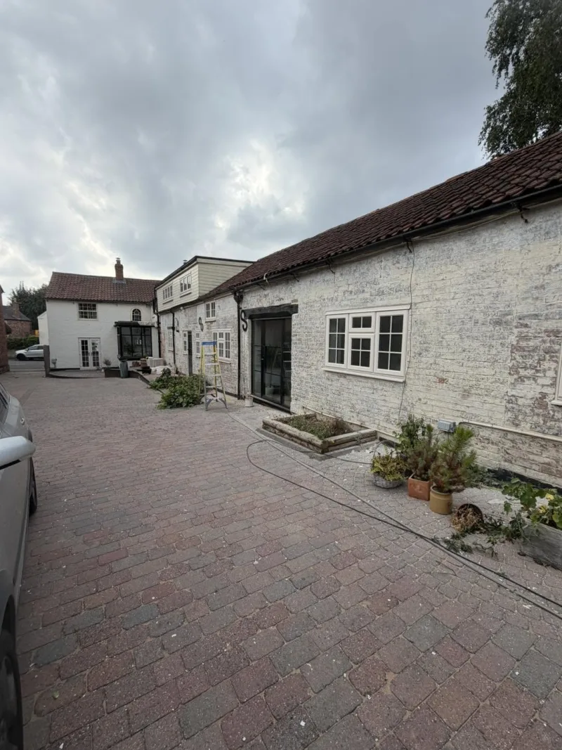 The same courtyard elevation before work, with flaking paint and failed mortar on the brickwork