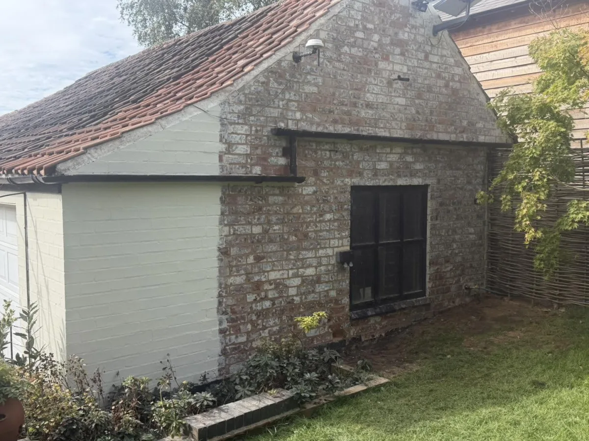 Repointed gable end in lime mortar next to a painted brick outbuilding