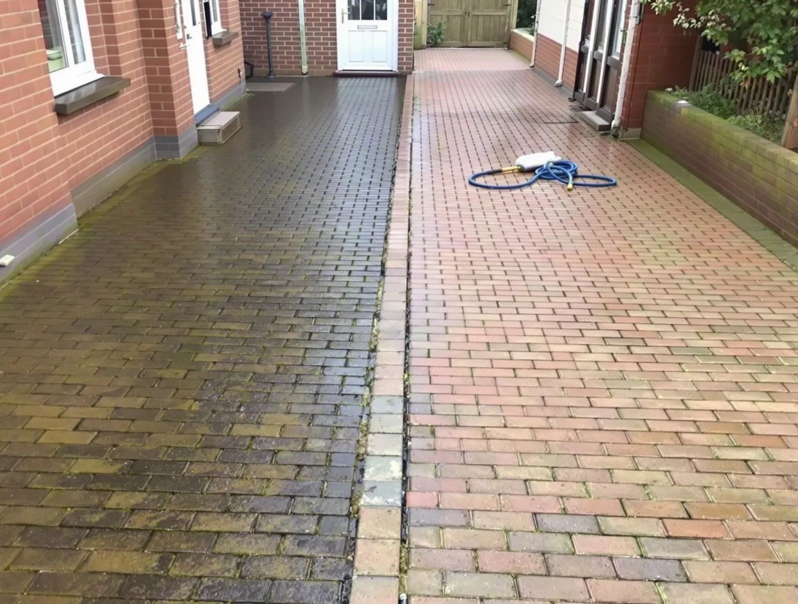 Block paved driveway half way through being cleaned, algae and grime on one side and clean block on the other